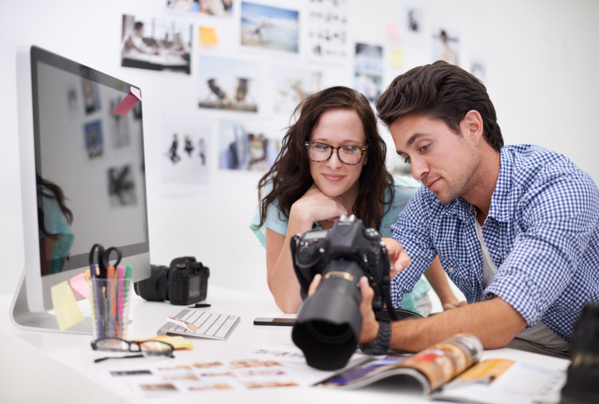 Two young photographers looking at photos on a digital camera in their studio